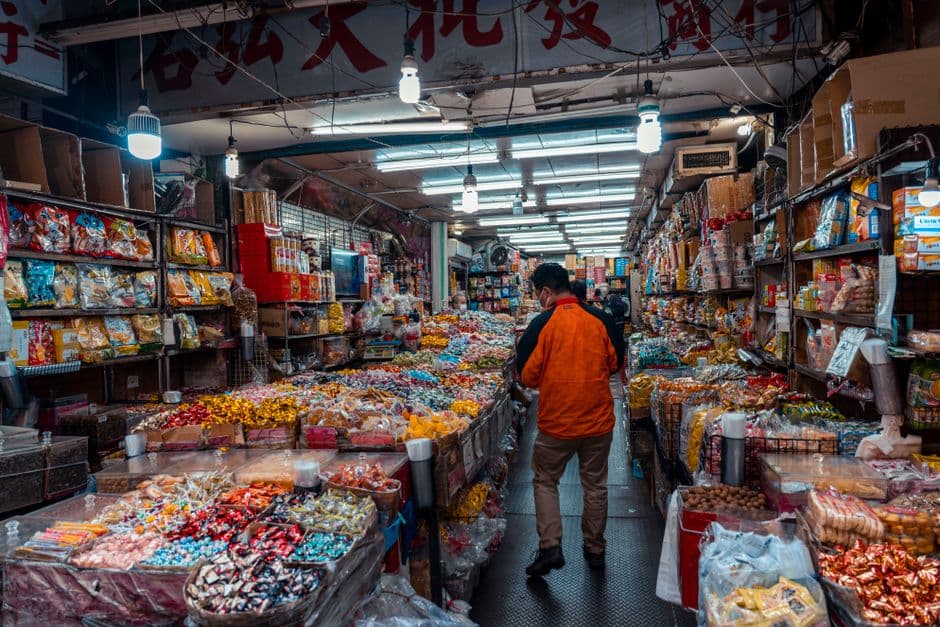 A man explores a bustling street market filled with colorful snacks and candies.